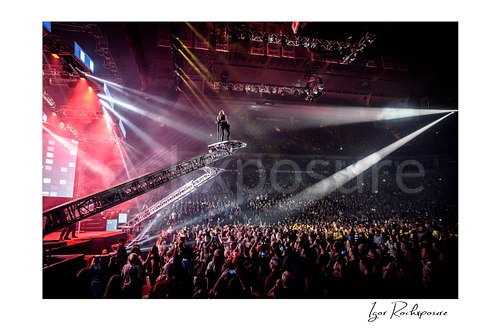 Horizontal color image of Chris Caffery of Trans Siberian Orchestra performing high above the crowd on an elevated stage ramp with bright arena spotlights