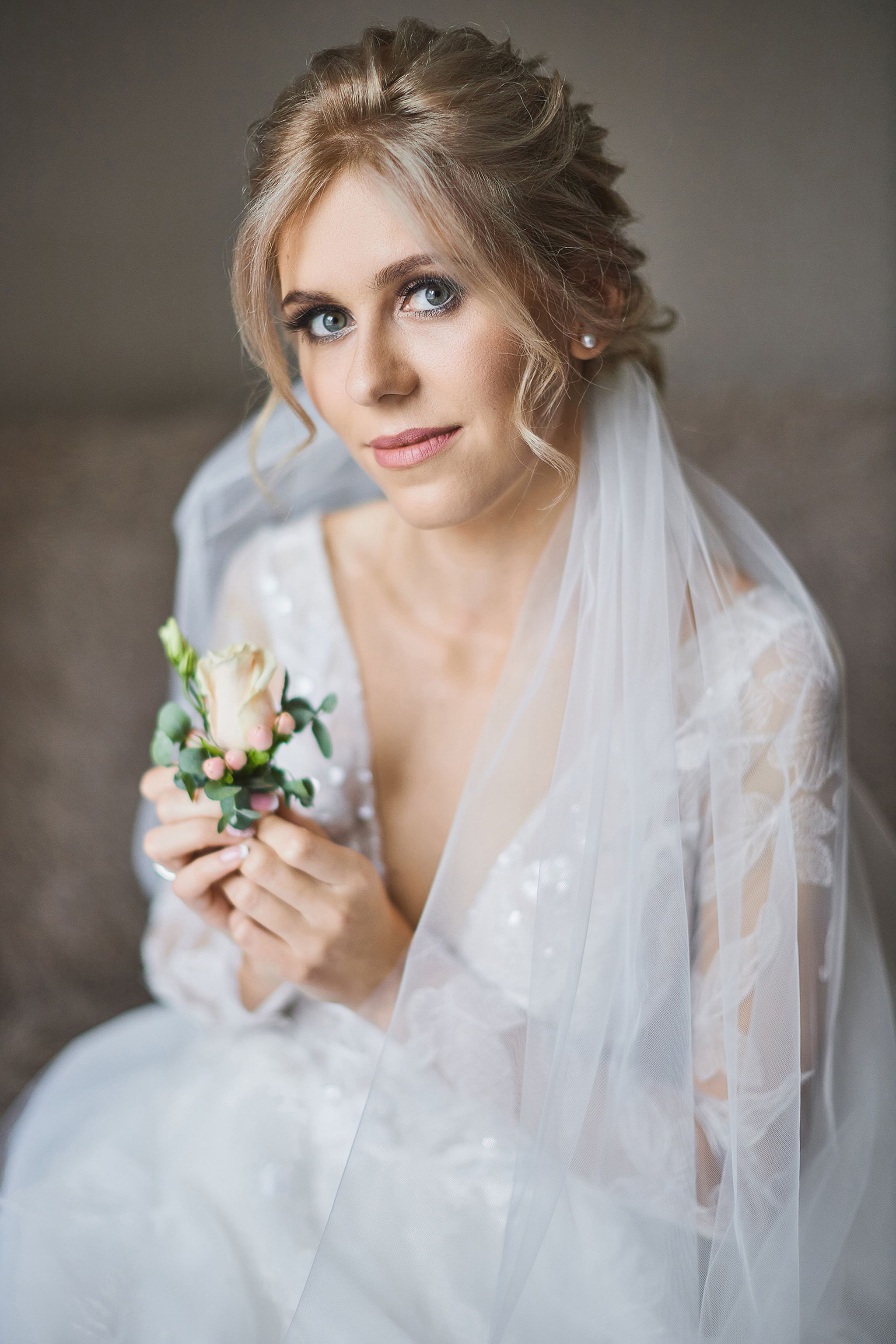 Bride holding a single rose in a timeless bridal portrait