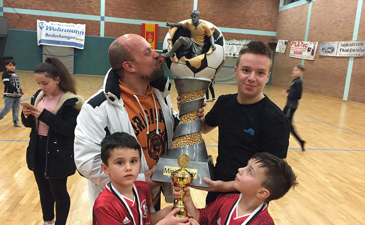 Stolze Minis präsentieren den riesigen Wanderpokal nach ihrem Turniersieg