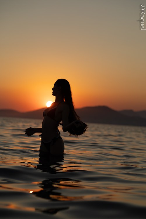 Silhouette d'une jeune femme dans la mer au coucher du soleil sur la côte de Hyères.
