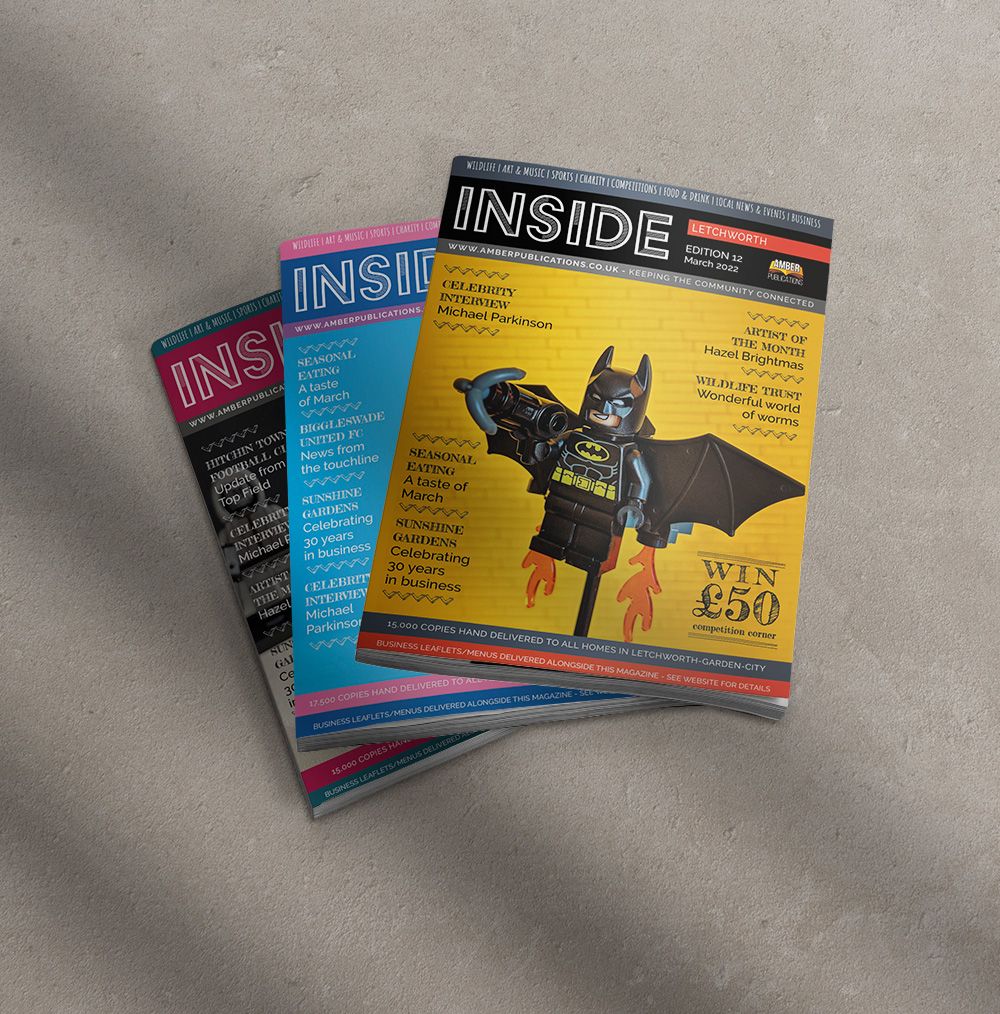 pile of local magazines the top one has a lego batman on the cover