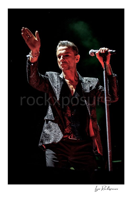 Vertical color image of Depeche Mode singer Dave Gahan performing beside a microphone stand during a live performance