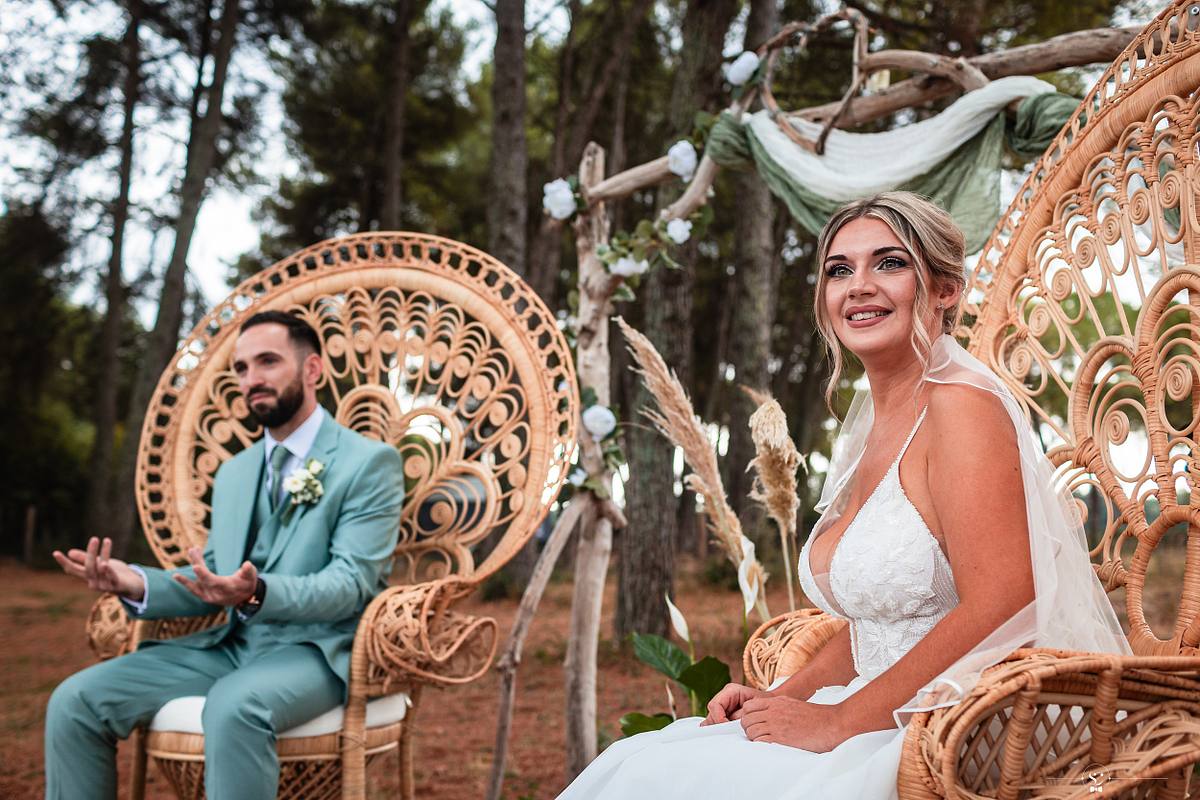 Mari&eacute;s rayonnants assis c&ocirc;te &agrave; c&ocirc;te, la mari&eacute;e souriante dans une robe blanche d&eacute;licate, lors d'une c&eacute;r&eacute;monie la&iuml;que dans une prairie pr&egrave;s de N&icirc;mes