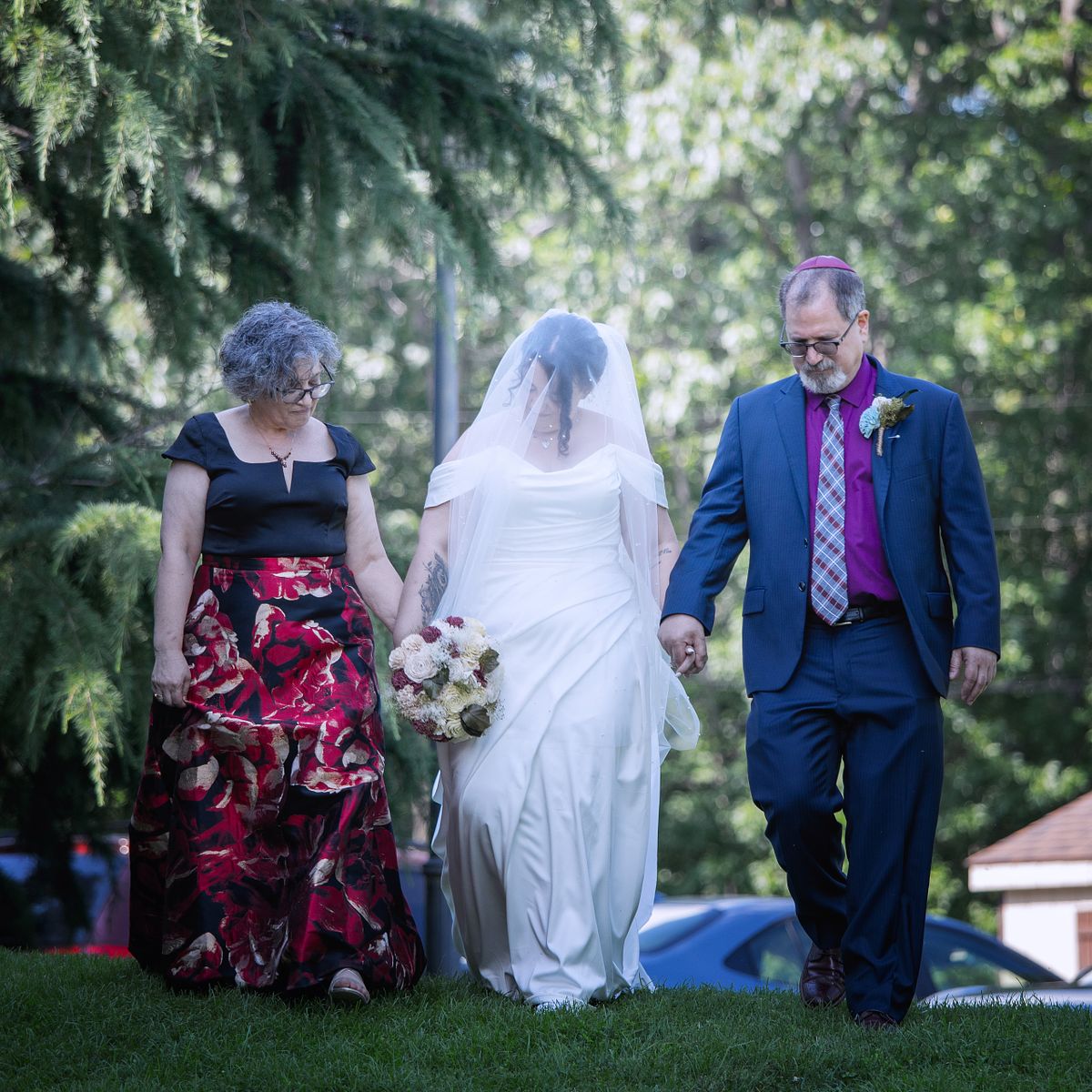 bride walking down with her parents at her side during a traditional jewish wedding