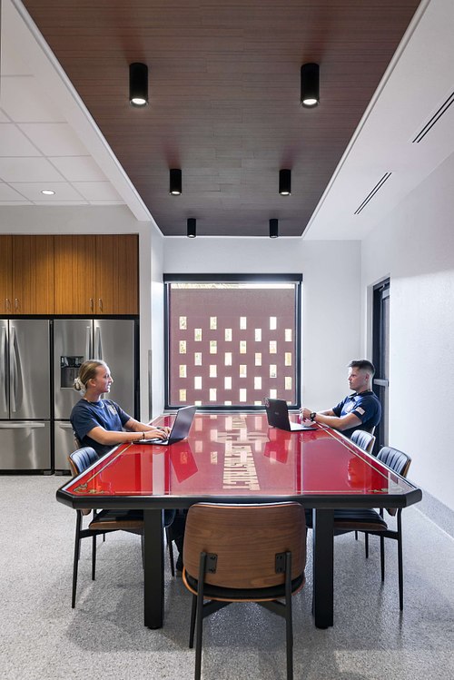 Architectural interior photography of the modern dining and kitchen area at Lealman Fire Station in Sarasota, designed by Sweet Sparkman Architecture, featuring warm wood ceilings and contemporary industrial finishes.