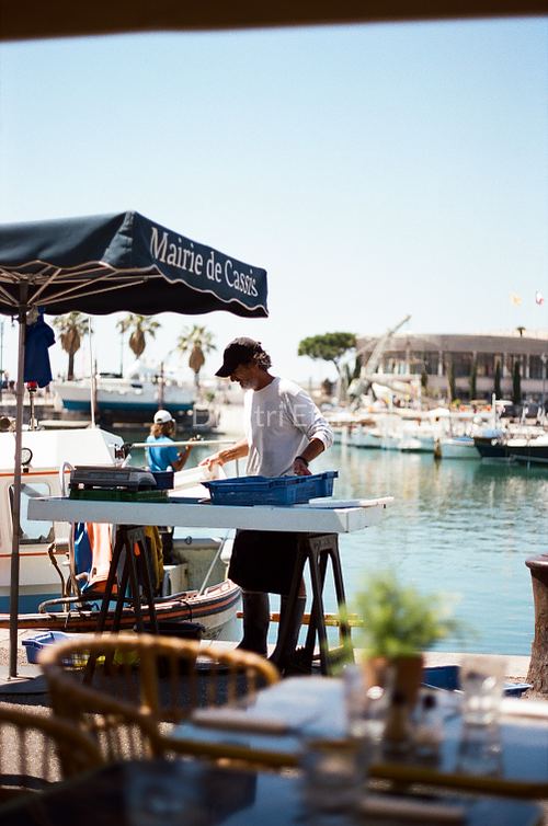 Photographie argentique d’un homme travaillant au bord du port de Cassis, dans une ambiance méditerranéenne, par Dimitri Eteni